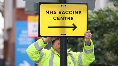 A Brent Council worker hangs a direction sign to the NHS Covid Vaccine Centre at the Olympic Office Centre, Wembley, north London, as ten further mass vaccination centres opened in England with more than a million over-80s invited to receive their coronavirus jab. Picture date: Monday January 18, 2021.